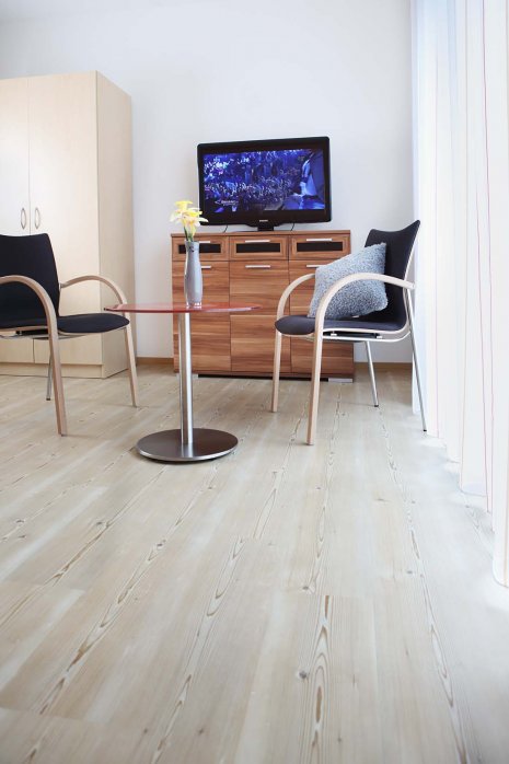 wineo PURLINE Bioboden im Seniorenheim Fernseher Stühle Tisch moderne Einrichtung Holzoptik Fußboden