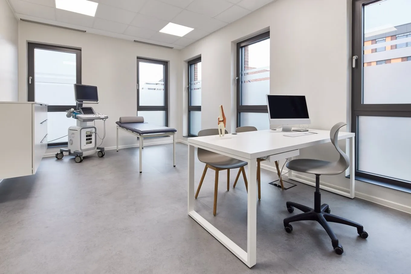 Behandlungszimmer mit moderner Einrichtung und grauem Bodenbelag im August Carree Oldenburg