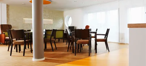 wineo PURLINE Bioboden im Altenpflege Bodeneblag grün Kantine Esszimmer Stühle Tische orange